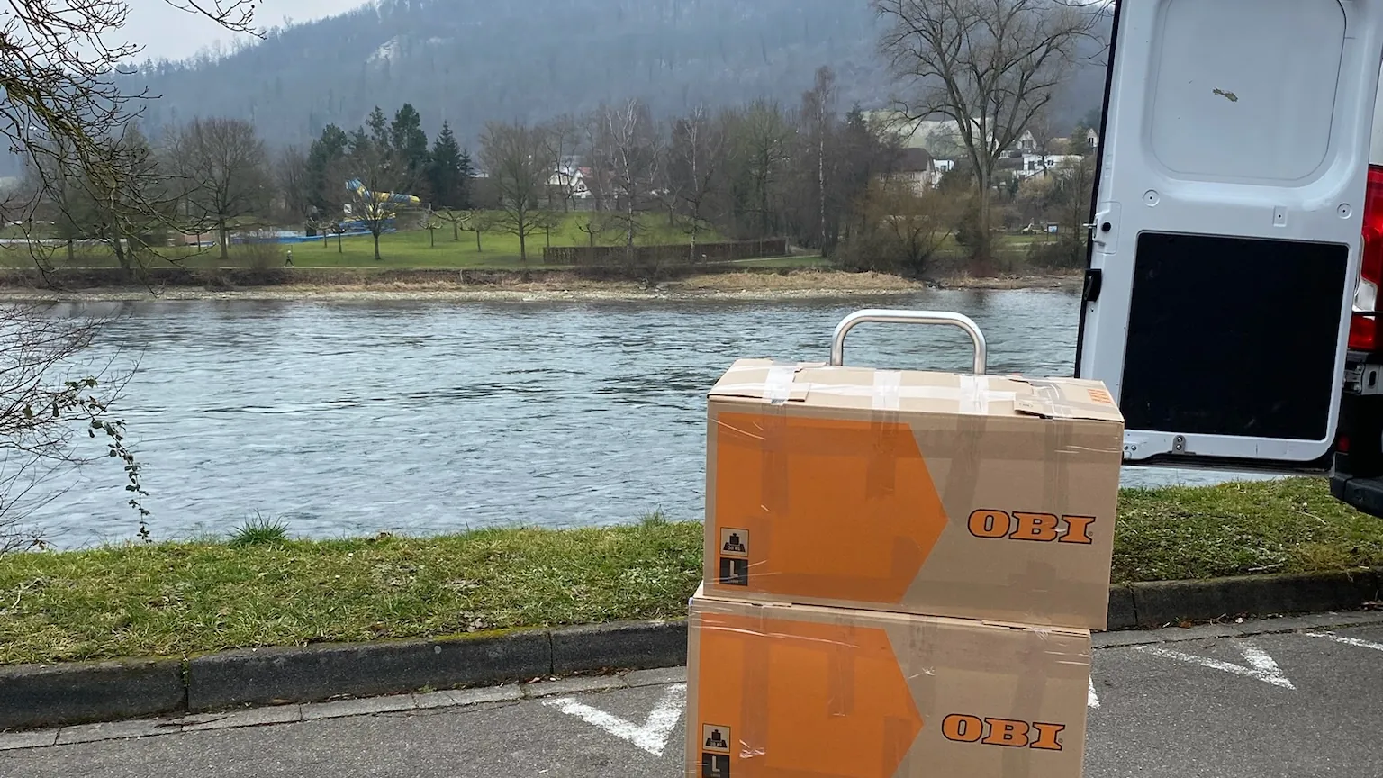 Cajas de mudanza junto a la furgoneta de Baipor, a orillas de un río en Suiza