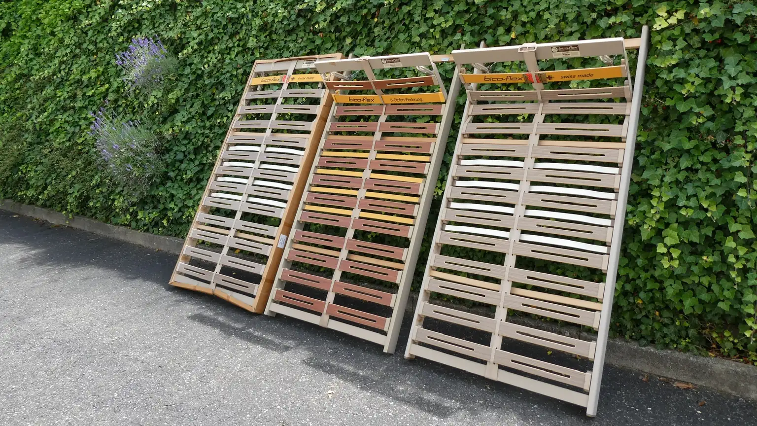 Von Baipor abgeholte gebrauchte Lattenroste an einer Efeumauer, bereit zur Wiederverwendung oder zum Recycling